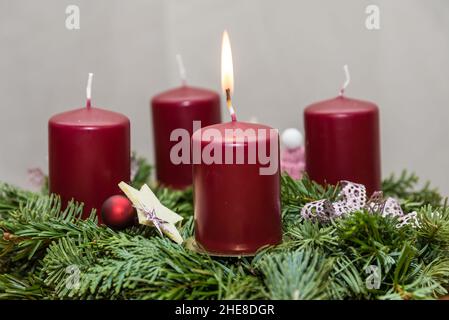 Die erste Kerze auf dem fir-grünen Adventskranz verbrnt - Adventszeit Stockfoto