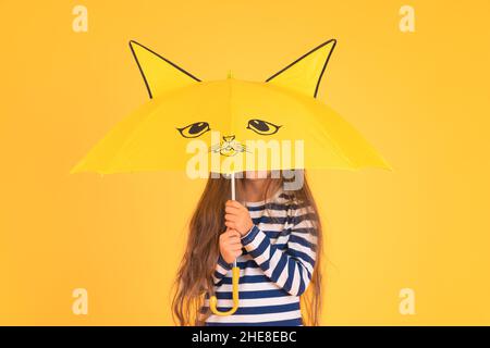 Glücklich emotionale Mädchen lachen mit Regenschirm auf farbigem gelben Hintergrund. Herbst, Frühjahrssaison. Stockfoto