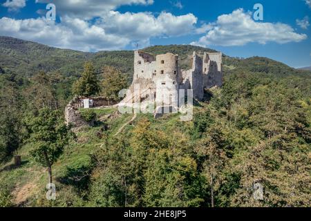 Luftaufnahme der unter Restaurierung mittelalterlichen Burg Reviste über dem Fluss Hron (Garam) in der Slowakei mit Bergfried, kreisförmigem Torturm, ruinierten gotischen Pala Stockfoto