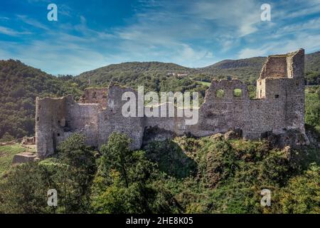 Luftaufnahme der unter Restaurierung mittelalterlichen Burg Reviste über dem Fluss Hron (Garam) in der Slowakei mit Bergfried, kreisförmigem Torturm, ruinierten gotischen Pala Stockfoto