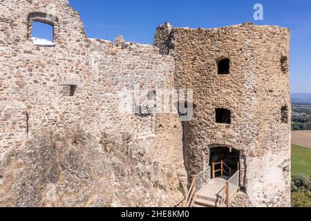 Luftaufnahme der unter Restaurierung mittelalterlichen Burg Reviste über dem Fluss Hron (Garam) in der Slowakei mit Bergfried, kreisförmigem Torturm, ruinierten gotischen Pala Stockfoto