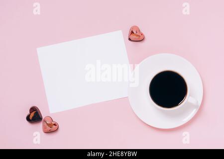 Schokolade Bonbons Herzen festliche Box, Tasse Kaffee, leeres Blatt Papier rosa Hintergrund. Konzept Valentinstag Stockfoto