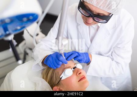 Kosmetologe tun Laser Warze Entfernung Verfahren für junge Frau Stockfoto