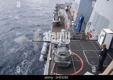 220107-N-TR141-0900 PHILIPPINISCHES MEER (JAN 7, 2022) Gunners Mate 2nd Klasse Joseph Brady, der dem Arleigh Burke-Klasse Lenkflugkörper-Zerstörer USS Dewey (DDG 105) zugewiesen wurde, steht zur Verfügung, während ein Mark 38 – 25 mm Maschinengewehr während einer Live-Feuertrainingsübung abfeuert. Dewey wird Destroyer Squadron (DESRON) 15 zugewiesen und unterstützt derzeit einen freien und offenen Indo-Pazifik-Raum. CTF 71/DESRON 15 ist die größte vorwärtseingesetzte DESRON-Flotte der Marine und die wichtigste Oberflächenkraft der US 7th-Flotte. (USA Navy Foto von Mass Communication Specialist 1st Klasse Benjamin A. Lewis) Stockfoto