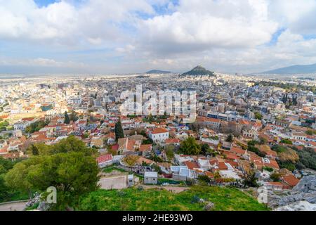 Blick auf die Bezirke Plaka und Monastiraki und den Berg Lycabettus von der Akropolis auf dem Akropolis-Hügel in Athen, Griechenland, an einem bewölkten Herbsttag. Stockfoto