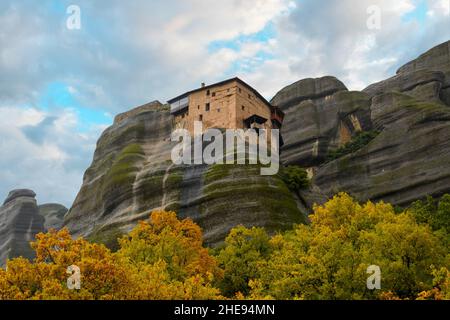 Heiliger Monastery of St. Nichola Anapafsasat Meteora, Griechenland unter nebligen, bewölkten Himmel mit Blättern, die im Herbst die Herbstfarben färben. Stockfoto