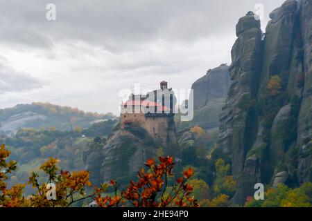 Heiliger Monastery of St. Nichola Anapafsasat Meteora, Griechenland unter nebligen, bewölkten Himmel mit Blättern, die im Herbst die Herbstfarben färben. Stockfoto