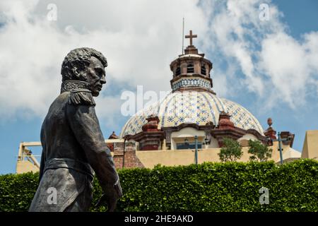 Statue des Staatsmannes Vicente Guerrero im Jardin Guerrero mit dem ehemaligen Kloster Santa Clara, das im alten Kolonialabschnitt von Santiago de Queretaro, Bundesstaat Queretaro, Mexiko, ragt. Stockfoto