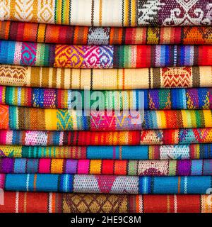 Stapel von bunten einheimischen Anden-Textilien oder -Stoffen, Otavalo-Markt in der Nähe von Quito, Ecuador. Stockfoto