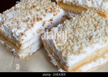 Mehrere individuelle Portionen Costrada auf einer Platte. Traditionelles süßes Blätterteig-Dessert, gefüllt mit Creme und Baiser und bedeckt mit gehacktem A Stockfoto