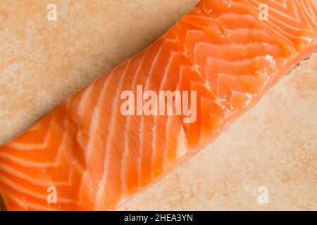Nahaufnahme des Fleisches eines frischen, rohen Lachses auf einem pastellfarbenen abstrakten, künstlerischen Texturhintergrund. Fisch und Essen. Stockfoto
