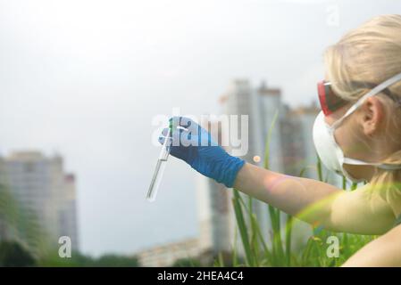 Frau mit Händen in Handschuhen hält ein Glas mit einer Wasserprobe. Probenahme aus offenem Wasser. Stockfoto