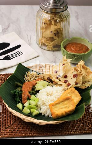 Nasi Pecel, traditionelles indonesisches Menü mit würziger Erdnusssauce, Tempeh, gekochtem Gemüse und gebratenen Tofu, Rempeyek, Beliebt für Frühstück, Abendessen, OP Stockfoto