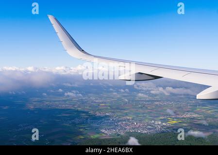 Blick auf den weißen Flugzeugflügel, der am blauen Himmel über Wolken fliegt. Stockfoto