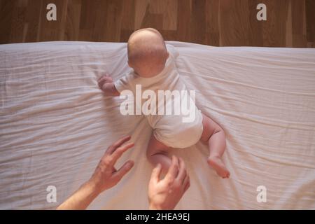 Kaukasisches Baby kriecht bis zum Rand des Bettes. Stockfoto