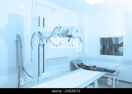 Röntgenabteilung im modernen Krankenhaus. Röntgenraum mit Scangerät und leerem Bett. Techniker, der ein Röntgengerät anpasst. Scannen von Brust, Herz Stockfoto