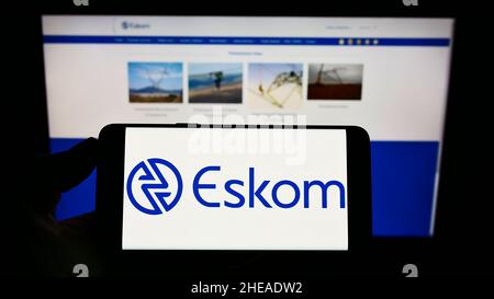 Person, die Mobiltelefon mit dem Logo des südafrikanischen Energieversorgers Eskom Holdings SOC Ltd. Auf dem Bildschirm vor der Webseite hält. Konzentrieren Sie sich auf die Telefonanzeige. Stockfoto
