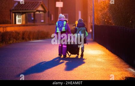 Laatzen, Deutschland. 10th Januar 2022. Zwei Schülerinnen und Schüler gehen am frühen Morgen auf dem Weg zur Schule in der Region Hannover zu ihrer Grundschule. In Niedersachsen beginnt der Schulunterricht nach den Weihnachtsferien mit täglichen obligatorischen Tests auf das Corona-Virus. Quelle: Julian Stratenschulte/dpa/Alamy Live News Stockfoto