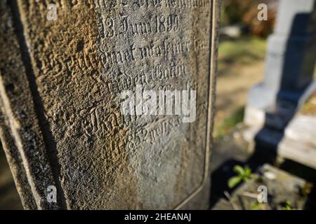 Sighisoara, Rumänien - 30. Oktober 2021: Details zur geringen Schärfentiefe (selektiver Fokus) mit dem Text in alter deutscher Sprache und Schriften auf einem Grab. Stockfoto