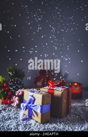 Wunderschöne Weihnachtsgeschenkschachteln auf dem Tisch mit Schnee im Zimmer. Schneefall Stockfoto