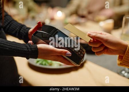 Nahaufnahme einer Frau, die mit einer Kreditkarte vom Kellner bezahlt hat, und sie, die für das Essen im Restaurant bezahlt hat Stockfoto