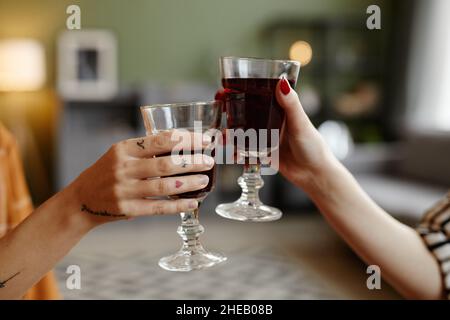 Nahaufnahme von Freunden, die Gläser mit Rotwein halten und während der Feiertagsfeier zusammen toasten Stockfoto