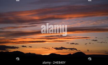 Schönes Licht und Wolken während des Sonnenuntergangs über dunklen Hügeln der Region Valenciana Stockfoto