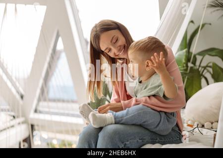 Glückliche Mutter, die die Socken auf ihr kleines Baby legt Stockfoto