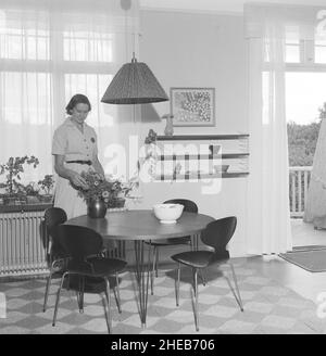 Die Designer des schwedischen String-Regals. Kajsa Strinning. Geboren am 27 1922. Januar, gestorben am 20 2017. Dezember. Die schwedische Architektin und Designerin hat sich hier in ihrem Haus und im Küchenbereich, wo ein String Bücherregal an der Wand zu sehen ist, gezeigt. Die Stühle werden von der dänischen Designerin Arne Jacobsen gefertigt und sind in der Ant oder in der dänischen Myren verkallt. Das Architektenpaar Nisse Strinning (1917-2006) und Kajsa Strinning (1922-2017) debütierte als Designer mit einem bescheidenen Blechgestell mit Stahldraht, einer Technik, die im Laufe der Jahre verfeinert werden sollte. 1949 kreierten sie einen skandinavischen Designklassiker, als The String s Stockfoto