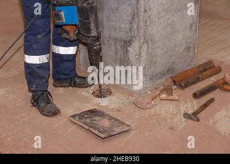 Arbeiter mit Presslufthammer. Männlicher Arbeiter bohrt und repariert Betonoberfläche mit Presslufthammer. Professioneller Arbeiter. Stockfoto