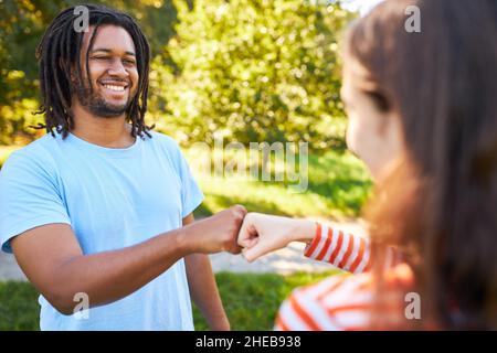 Zwei Freunde grüßen sich im Sommer in der Natur cool und lässig mit Fist Bump Stockfoto