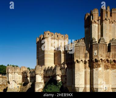 Spanien, Kastilien und Leon, Provinz Segovia. Coca Castle. Es wurde Ende des 15th. Jahrhunderts vom kastilischen Magnaten Don Alonso de Fonseca erbaut. Mudejar-Stil. Zinnen eines Turms. Architektonisches Detail von außen. Stockfoto