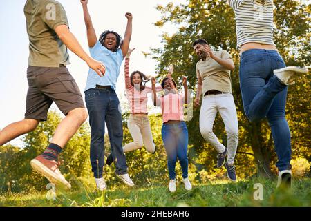 Gruppe junger Menschen als Freunde, die im Sommer in der Natur jubeln und springen Stockfoto