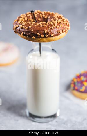 Auswahl von Donuts mit verschiedenen Farben auf grauem Hintergrund mit einem Glas Milch Stockfoto