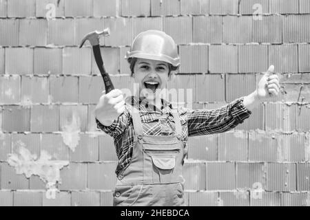 Fröhliche Kinderarbeiter mit Gebäude Uniform und Hammer-Werkzeug, Arbeiter Stockfoto