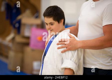 Weißrussland, die Stadt Gomel, 23. Juni 2021. Judo Club. Ein Kind mit Down-Syndrom in der Turnhalle mit einem Trainer. Stockfoto