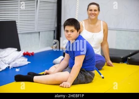 Weißrussland, die Stadt Gomel, 23. Juni 2021. Judo Club. Ein Kind mit Down-Syndrom in der Turnhalle vor dem Hintergrund der Mutter. Stockfoto