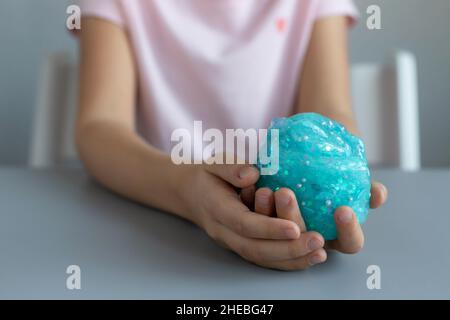Vorschulmädchen hält blauen Glitzer Schleim. Spaß sensorische Spielzeug für Kinder Stockfoto