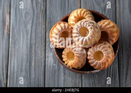 Frisch gebackene hausgemachte Muffins in einer Keramikschale auf Holzboden Stockfoto