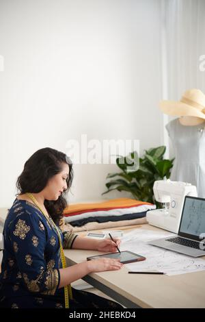 Talentierte kreative Schneiderdrawing Mode Skizzen auf Tablet-Computer Stockfoto