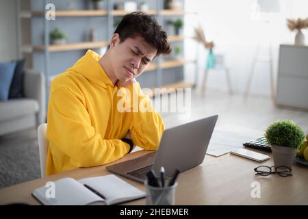Gestresster asiatischer Mann, der am Schreibtisch mit pc sitzt Stockfoto