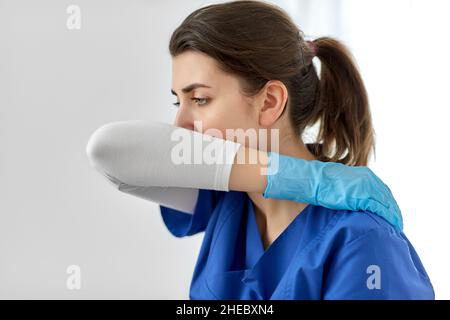 Arzt oder Krankenschwester hustet, wobei der Mund mit dem Ellbogen bedeckt ist Stockfoto