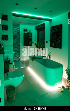 Modernes Badezimmer mit freistehender Badewanne, modernen Armaturen und grüner LED-Beleuchtung Stockfoto