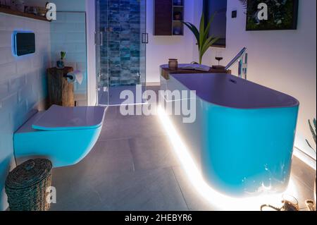 Modernes Badezimmer mit freistehender Badewanne, modernen Armaturen und LED-Umgebungsbeleuchtung Stockfoto