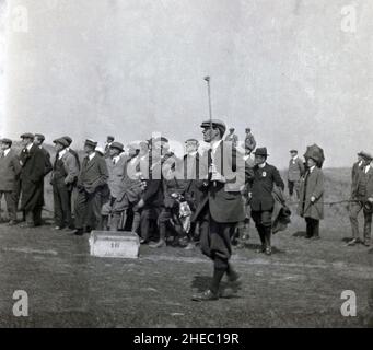 Um 1910, historisch, Golfer auf einem Links-Golfplatz, ein männlicher Golfer in der Golfkleidung des Tages, Eiter zwei Abschlagen eines Abschlages, beobachtet von Zuschauern, England, Großbritannien. Stockfoto