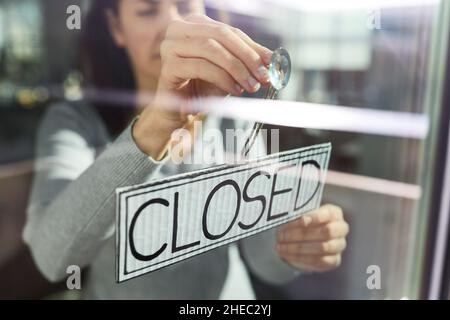 Frau hängend Banner mit geschlossenen Wort an der Tür Stockfoto