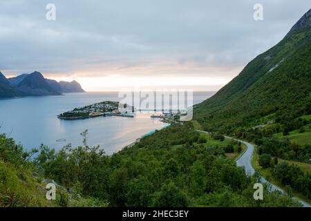 Luftaufnahme von Husoy, einem kleinen Dorf auf einer winzigen Insel, die zur großen Insel Senja gehört und von einer wunderschönen Berglandschaft umgeben ist Stockfoto