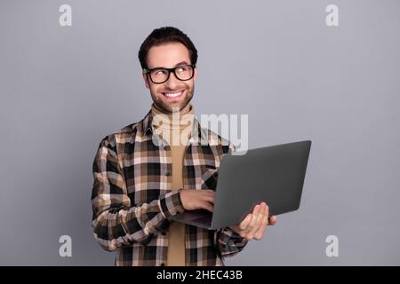 Portrait von attraktiven neugierig fröhlich erfahrenen Kerl Experte mit Laptop denken kopieren Raum isoliert über grauen Hintergrund Stockfoto