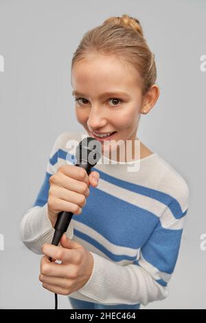 Lächelndes Mädchen im Teenageralter mit Mikrofon-Gesang Stockfoto