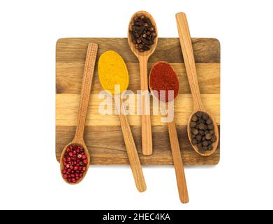 Weißer Hintergrund, isoliert, fünf Löffel mit Gewürzen liegen auf Holzschneidebrett Stockfoto